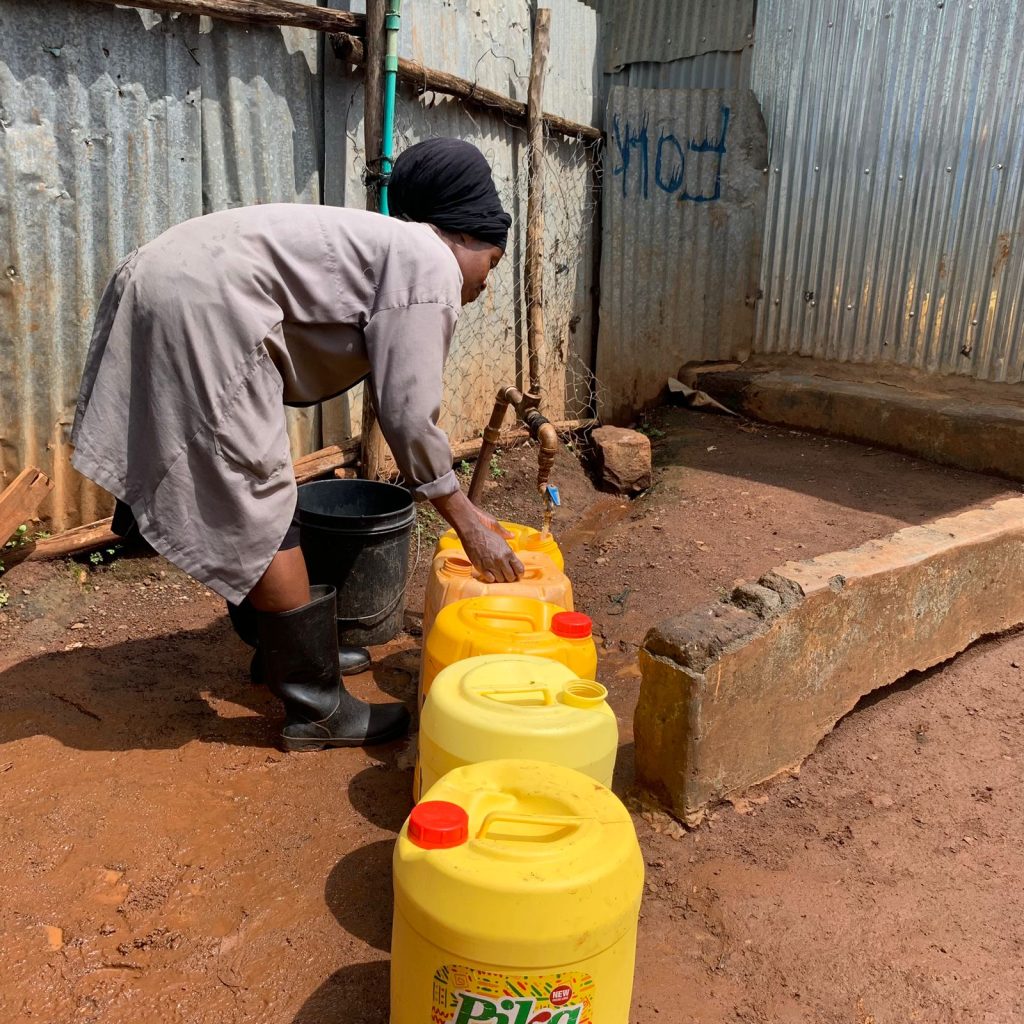 A woman filling yellow water containers at a water point
